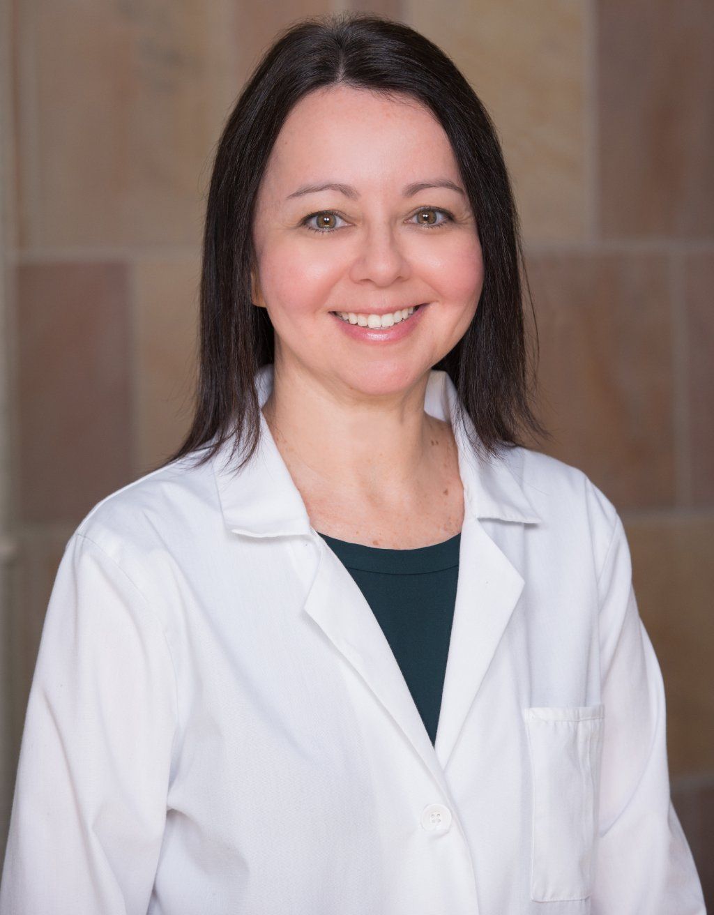 Ann Wexler, M.D. in a white lab coat is smiling for the camera