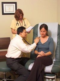 A doctor is listening to a patient's heartbeat with a stethoscope.