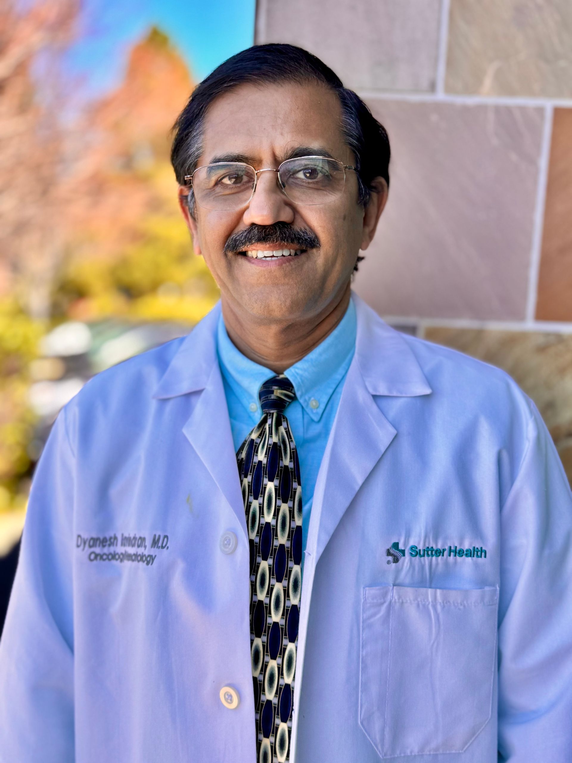 Dyanesh Ravindran, M.D. in a suit and tie is smiling for the camera.