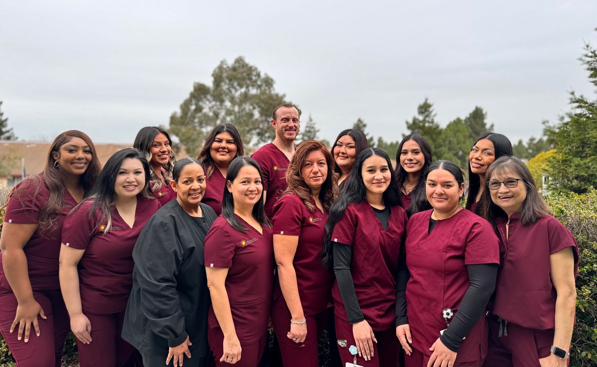 A group of people wearing purple scrubs are posing for a picture.