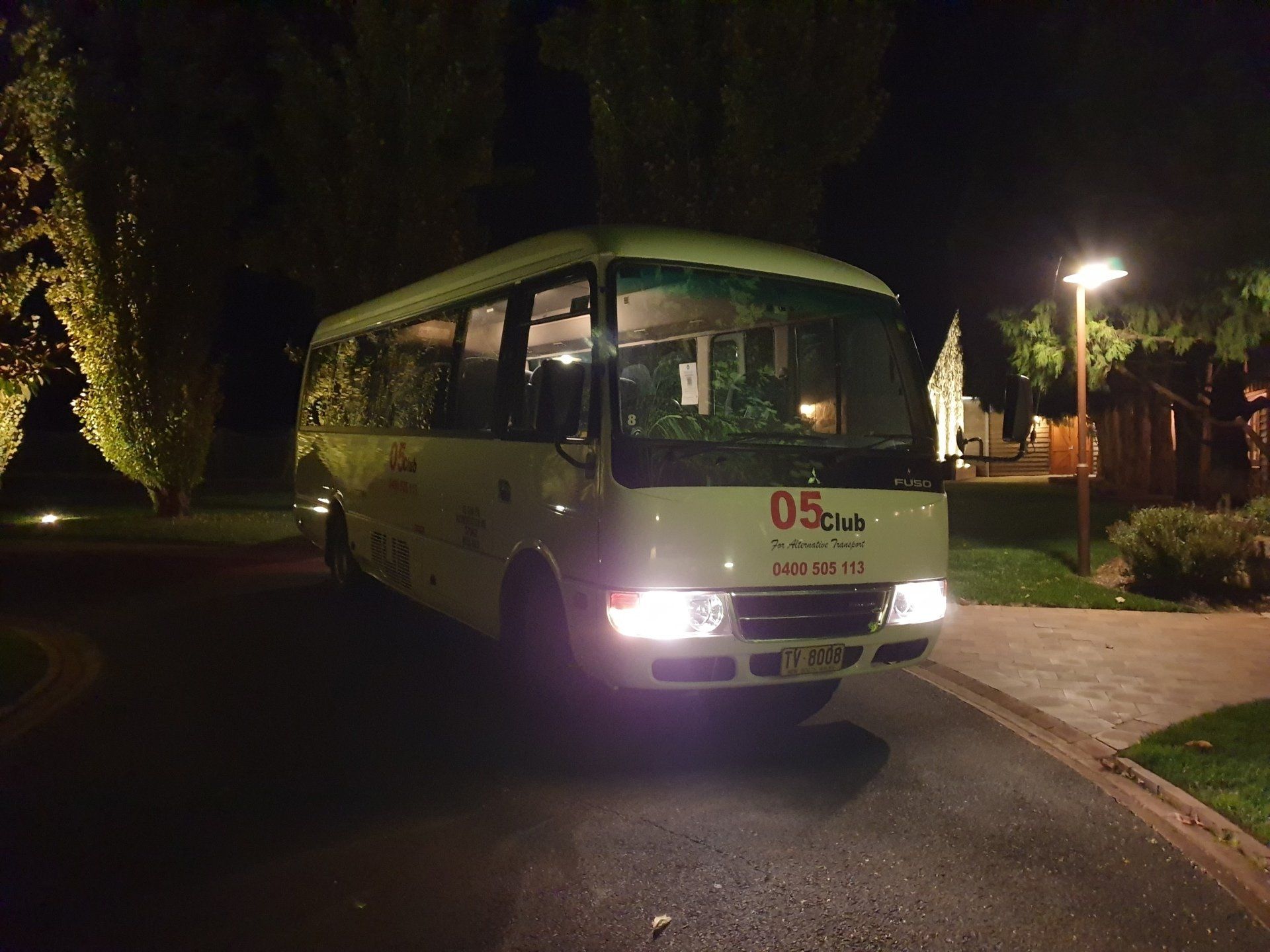 A white bus is parked on the side of the road at night.