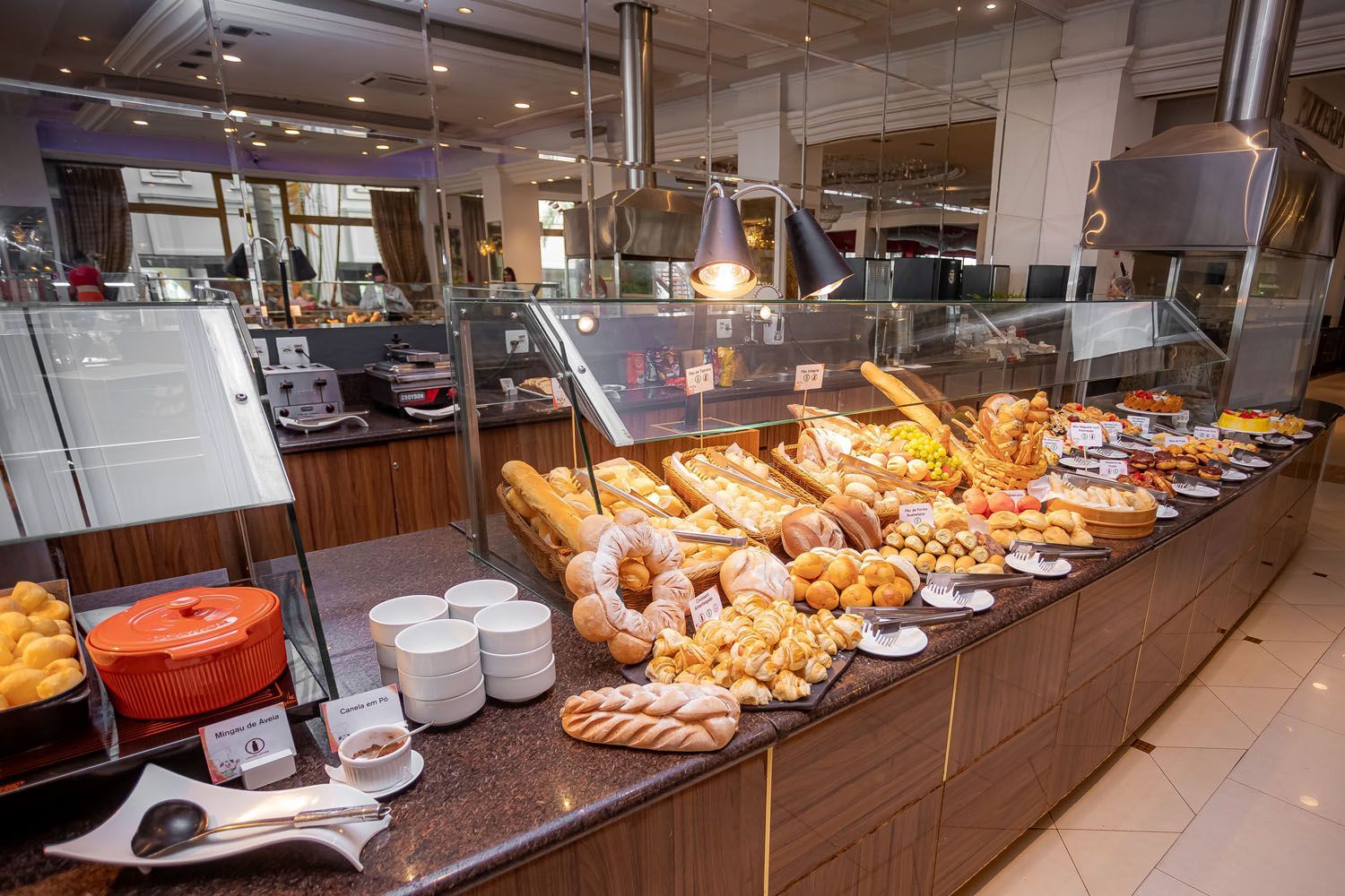 Uma mesa de bufê repleta de vários pães, doces e outros alimentos de café da manhã em uma área de jantar.
