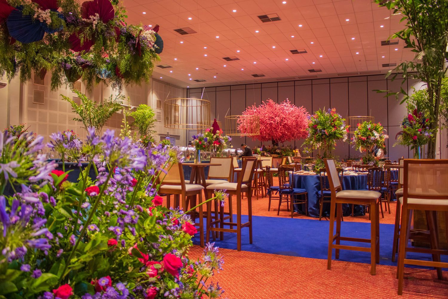 Uma grande sala cheia de mesas, cadeiras e flores.