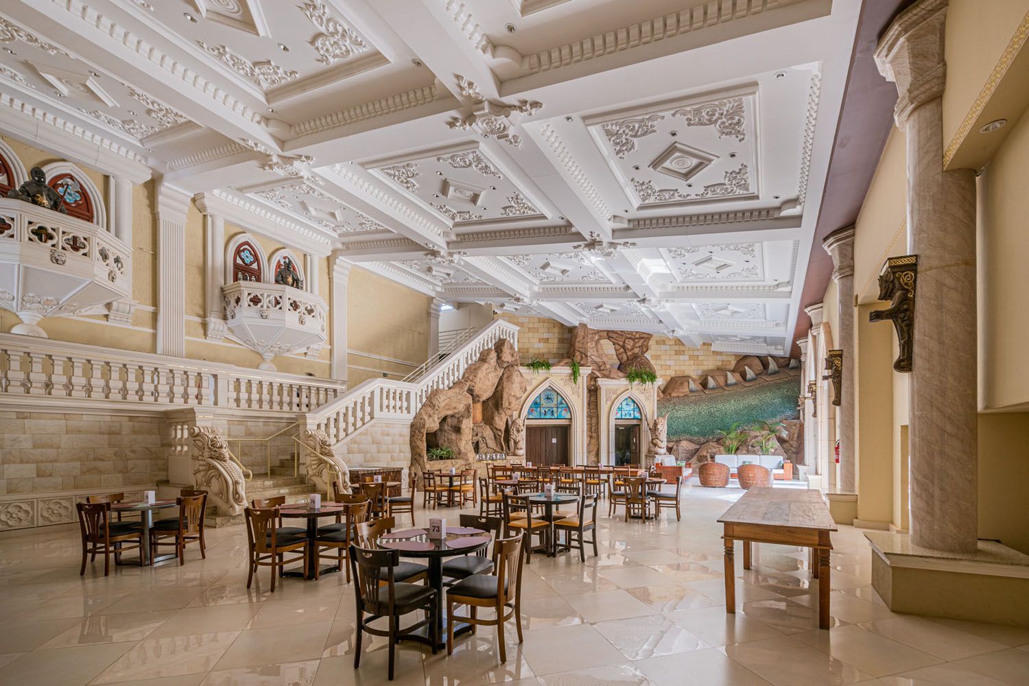 Uma grande sala de jantar com mesas e cadeiras e escadas.