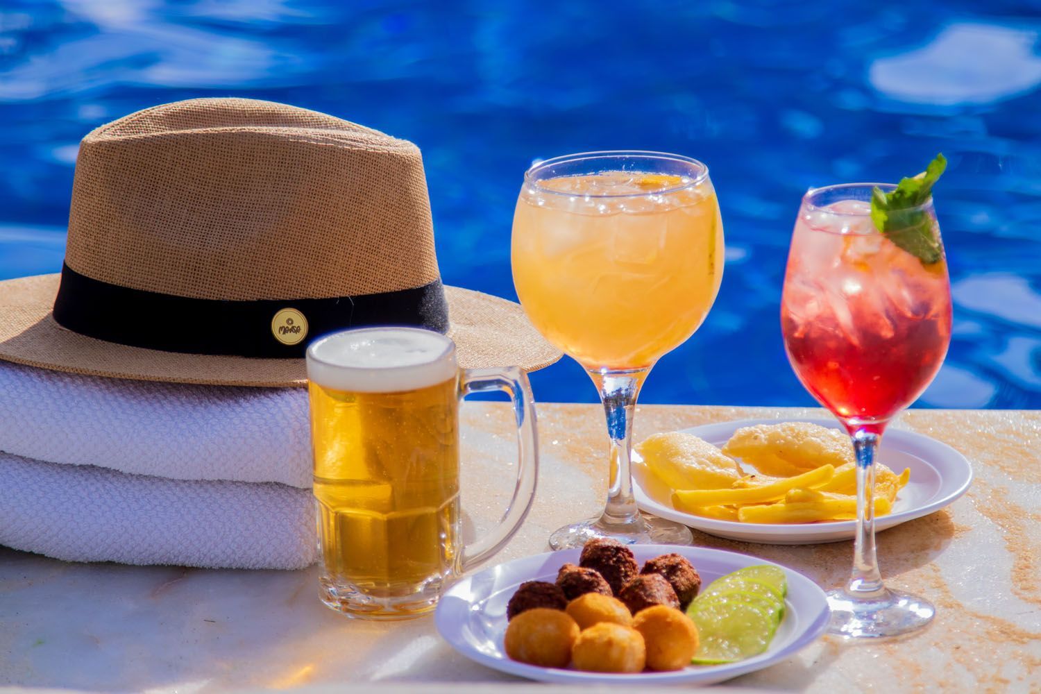 Chapéu, bebidas, petiscos e cerveja à beira da piscina. Dia ensolarado, cores vibrantes, relaxamento.