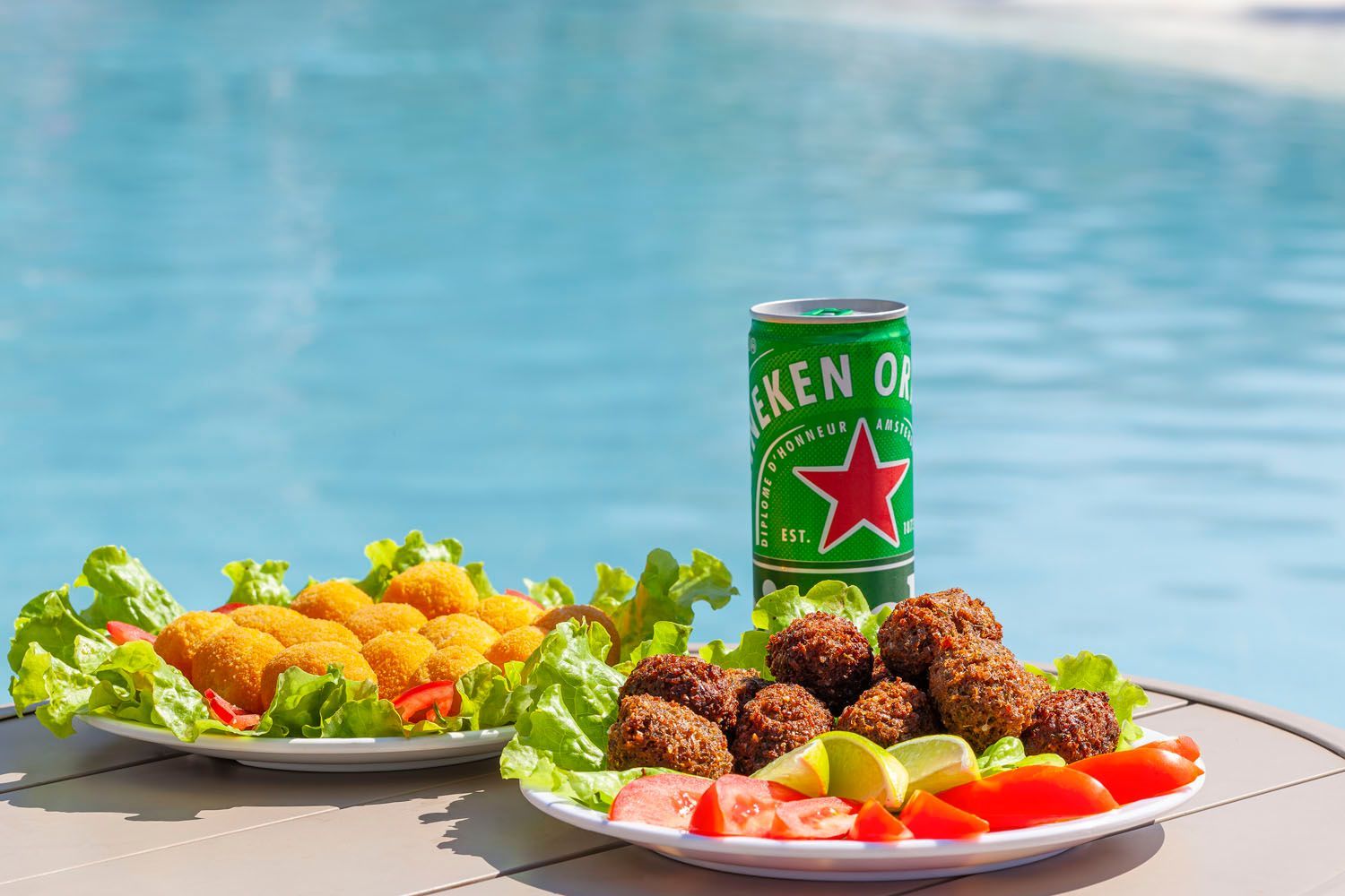 Aperitivos em pratos com uma lata de Heineken à beira da piscina.