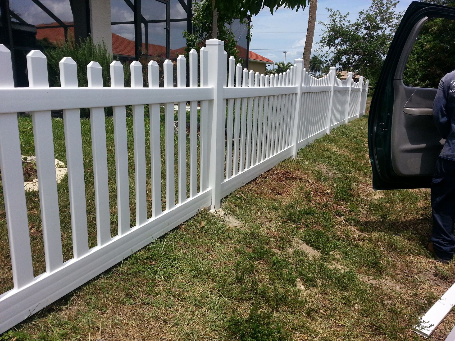 A man is standing next to a white picket fence