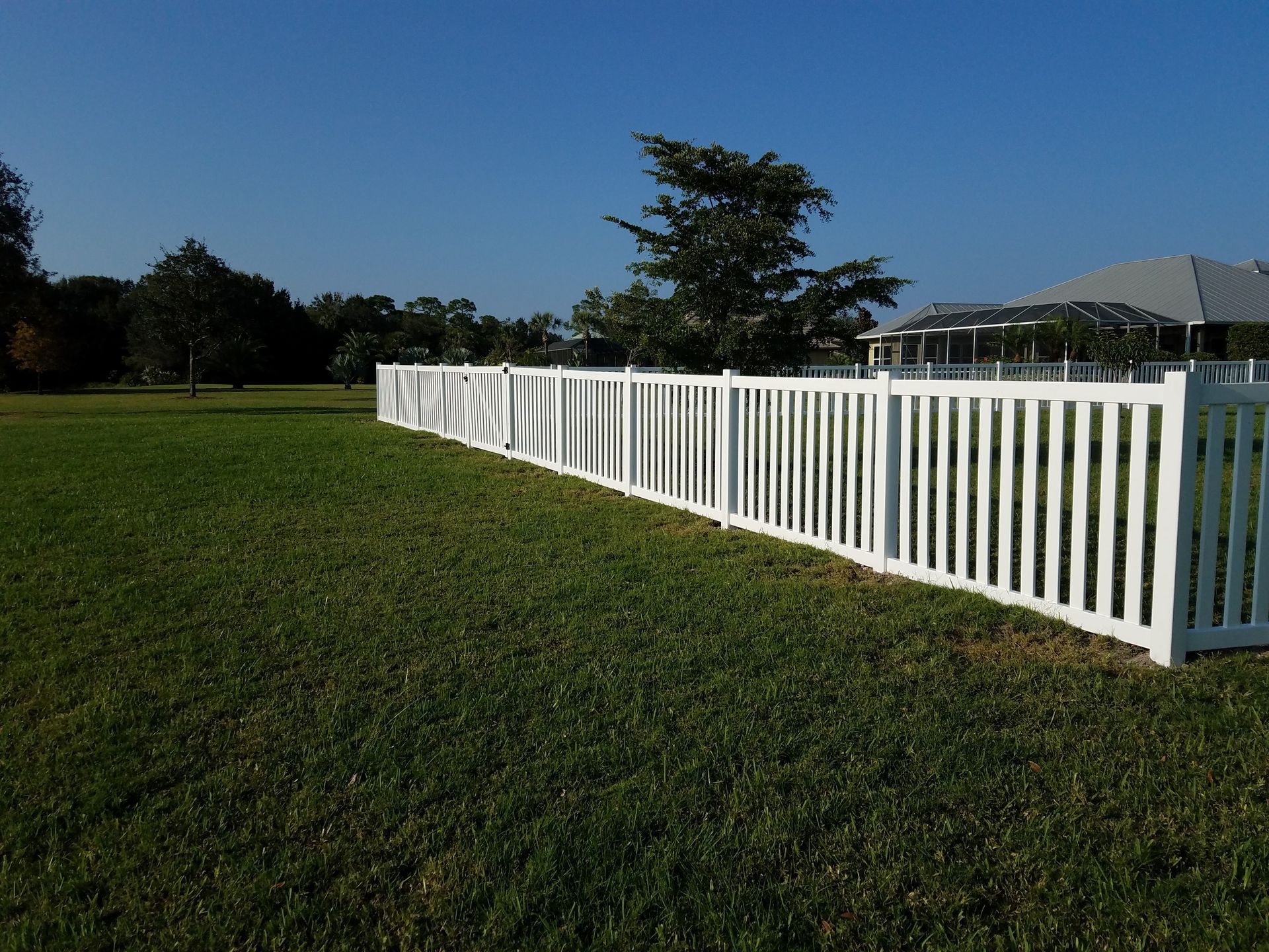 A white fence surrounds a lush green field.