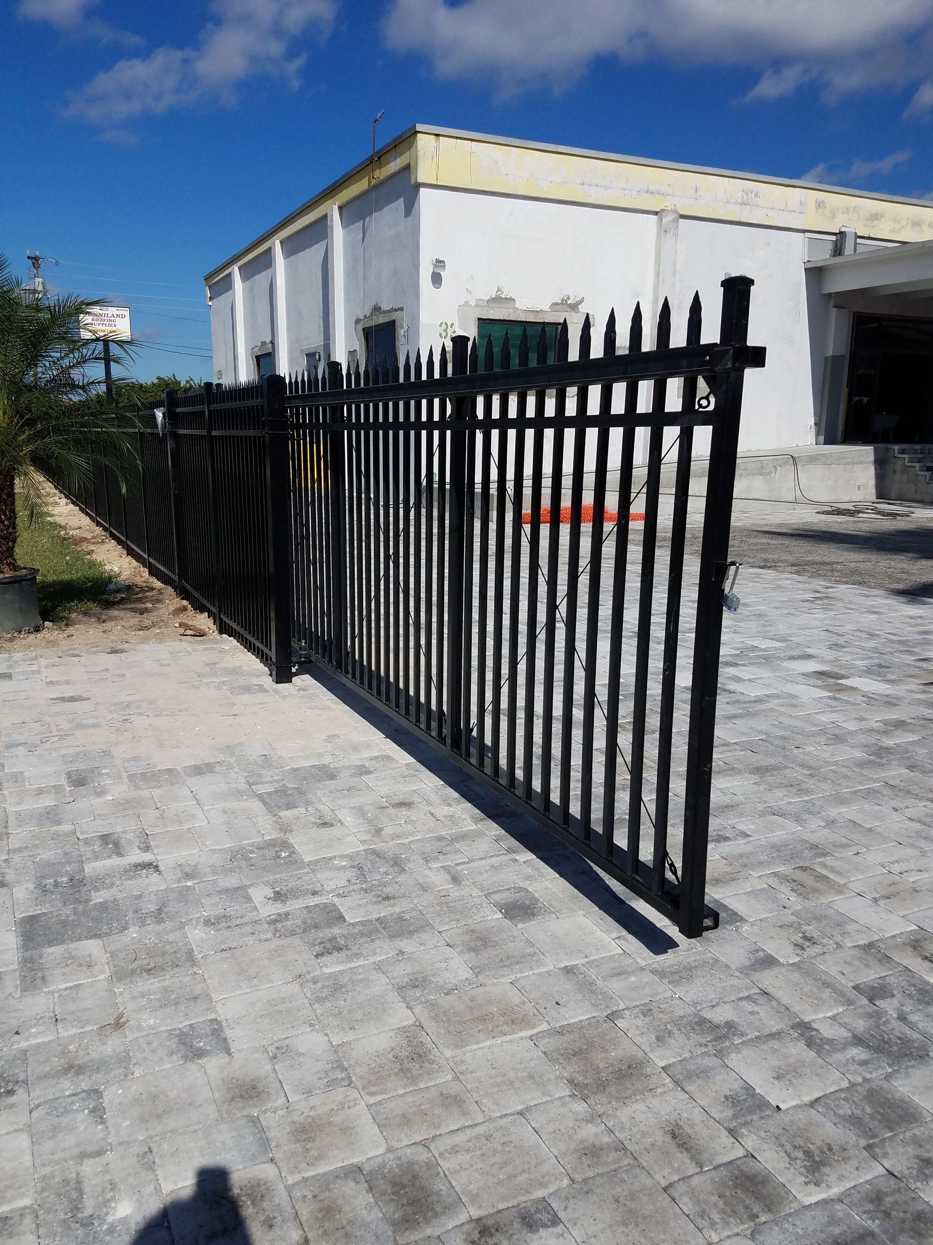 A black fence with a white building in the background