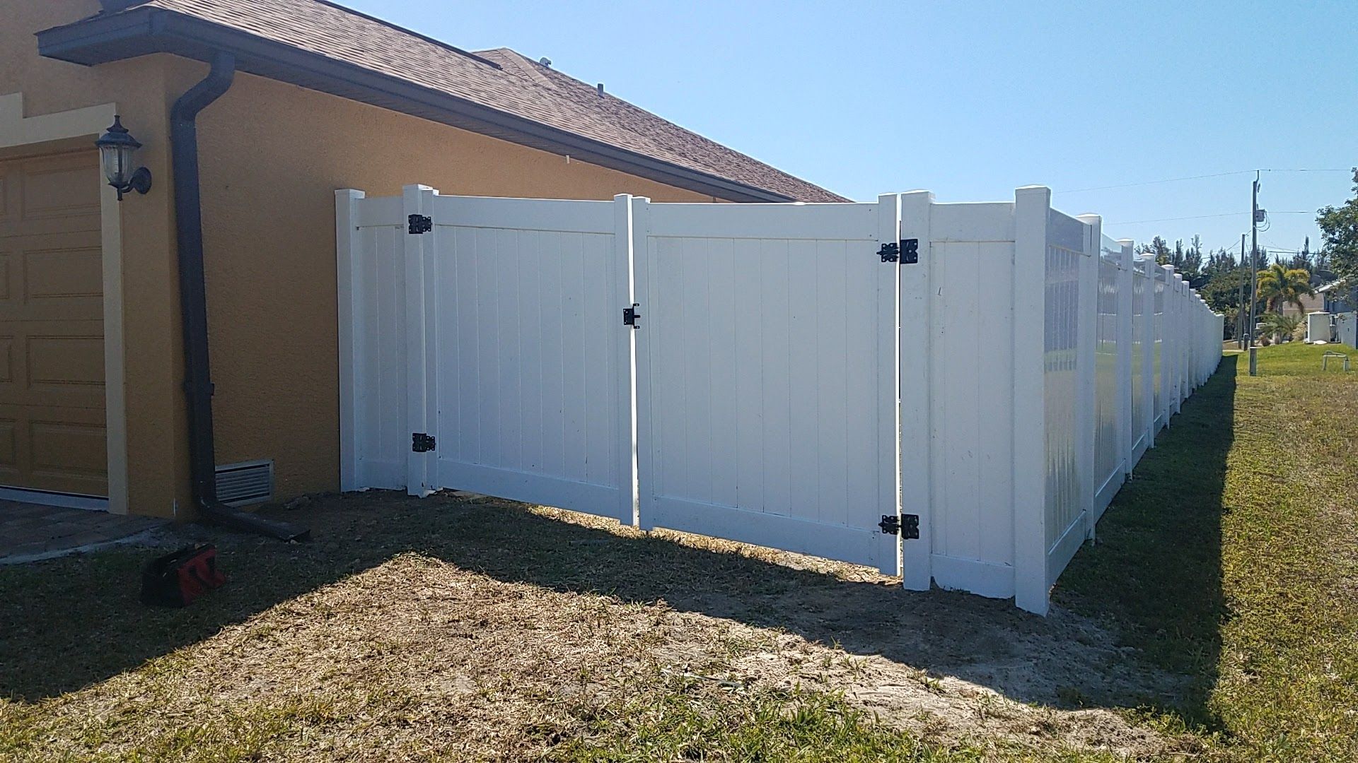 A white fence with a gate is in front of a house.