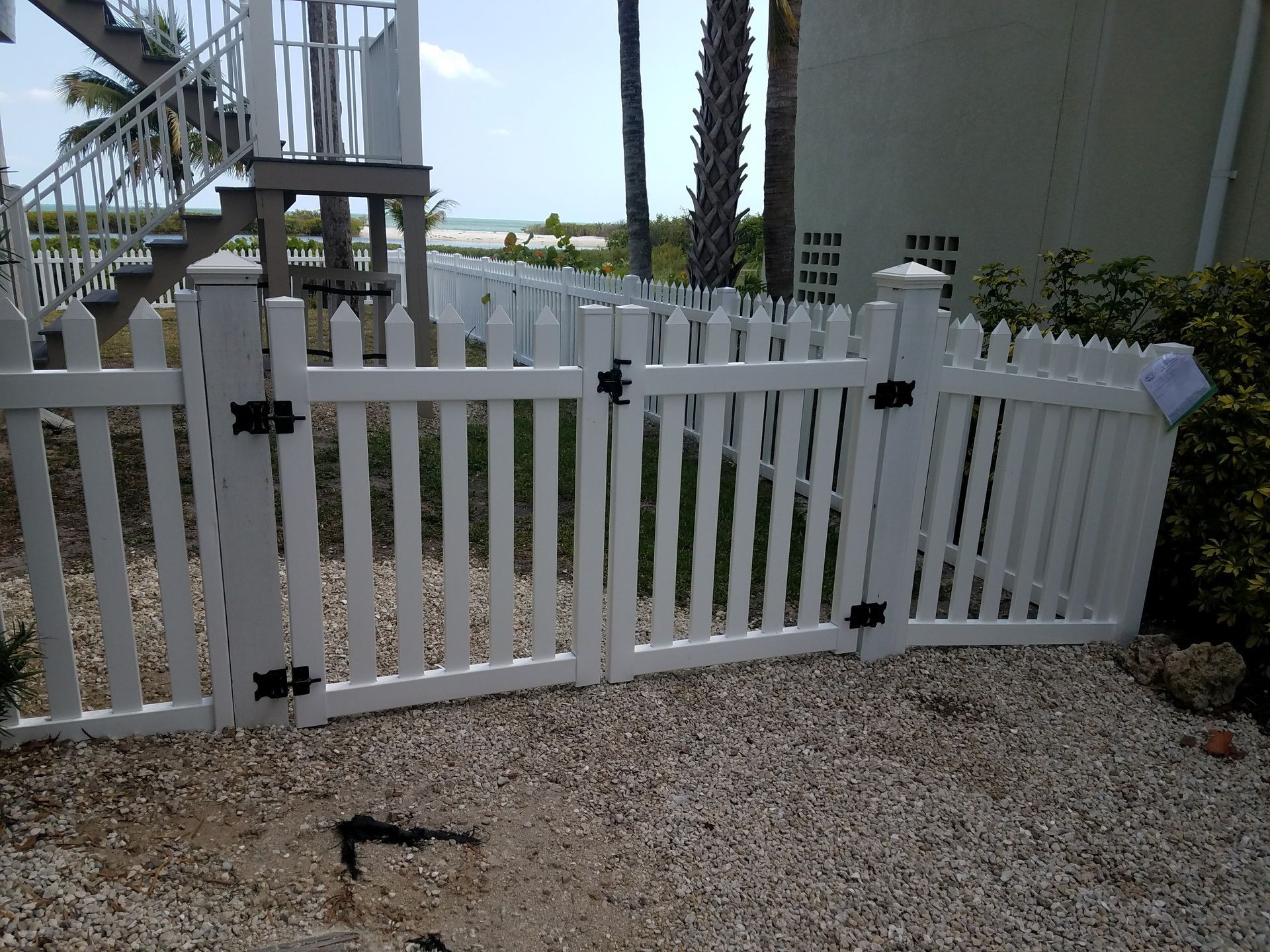 A white picket fence with a gate in front of a house