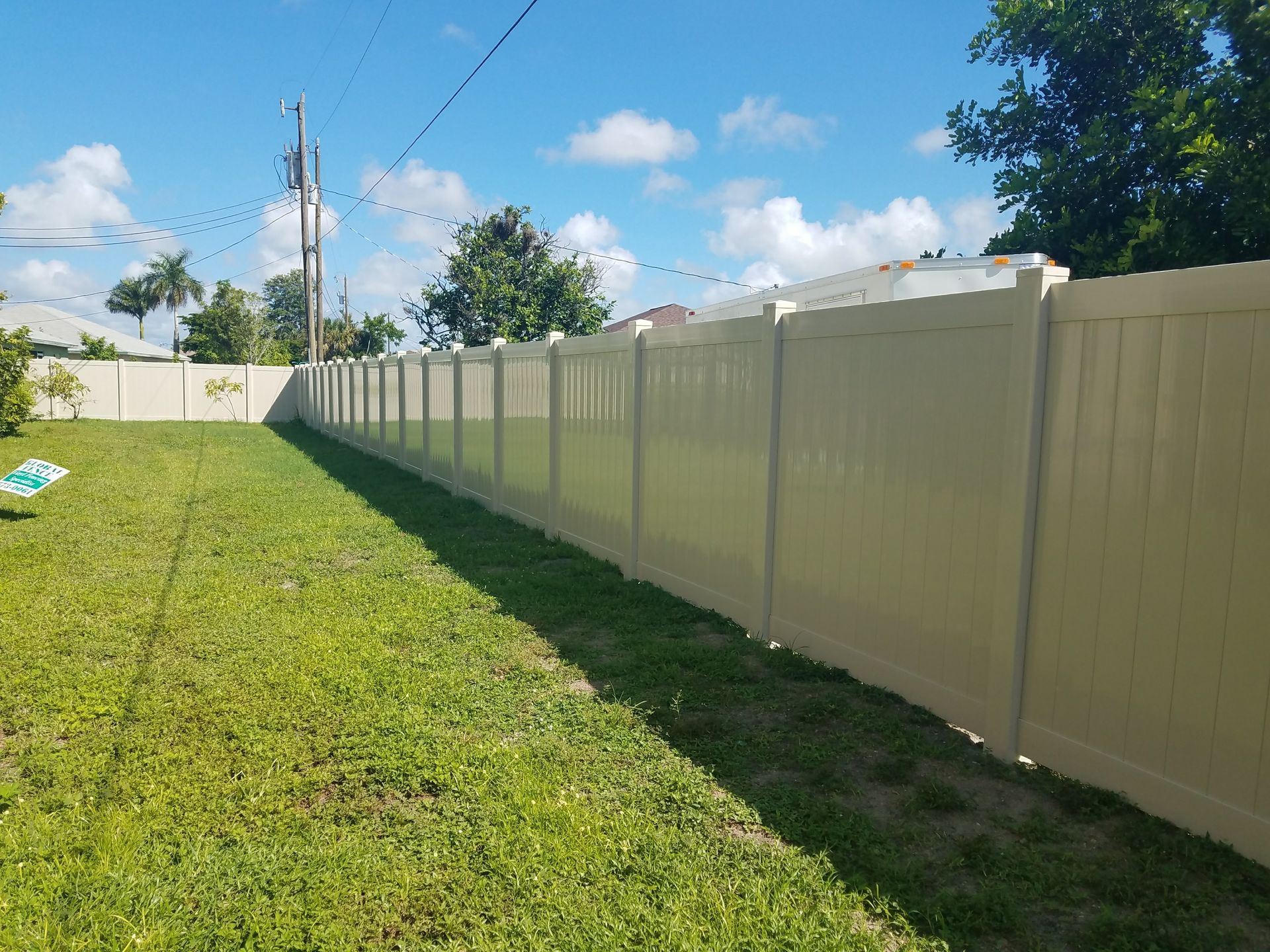 A long white fence surrounds a lush green field.