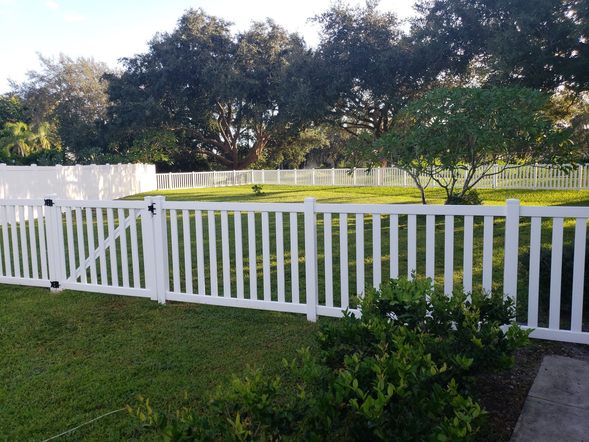 A white picket fence surrounds a lush green yard.