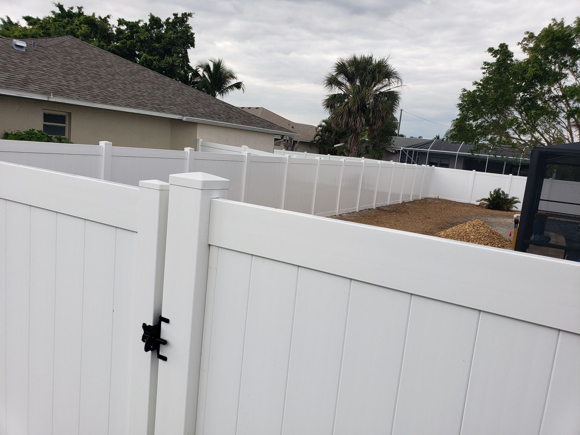 A white vinyl fence with a gate in front of a house.