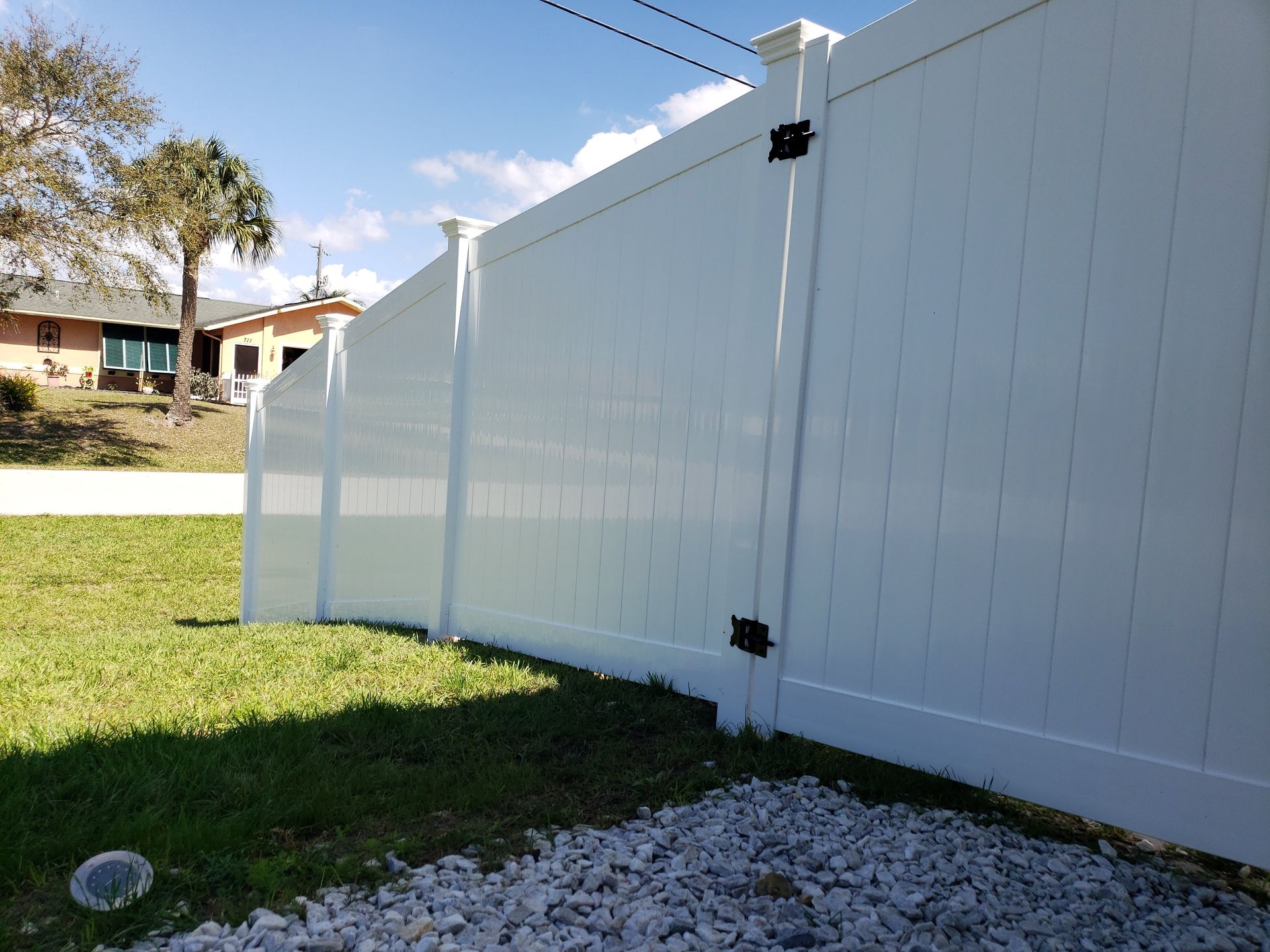 A white vinyl fence is sitting in the grass in front of a house.