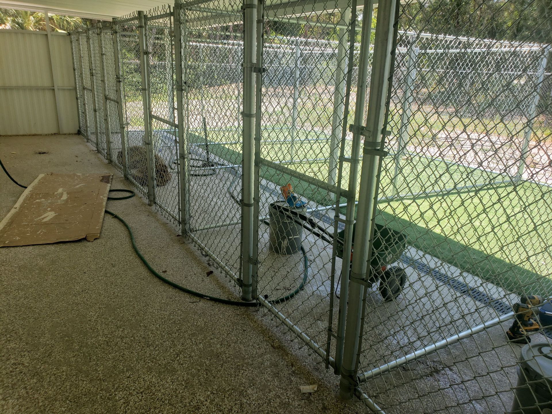 A chain link fence is surrounding a room with a hose attached to it.