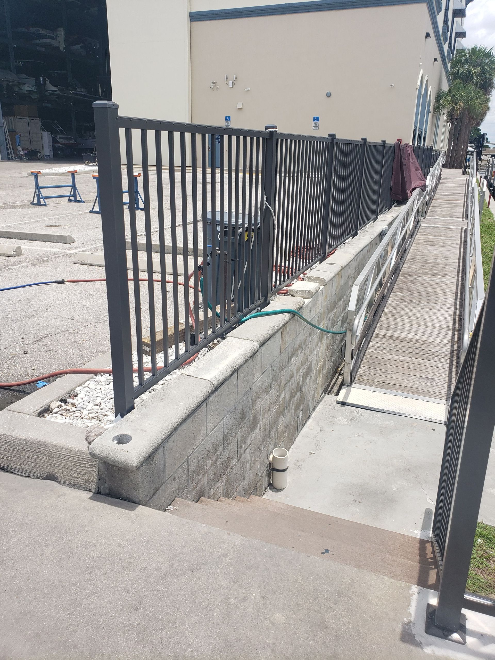 A fence is being built around a concrete wall next to a building.