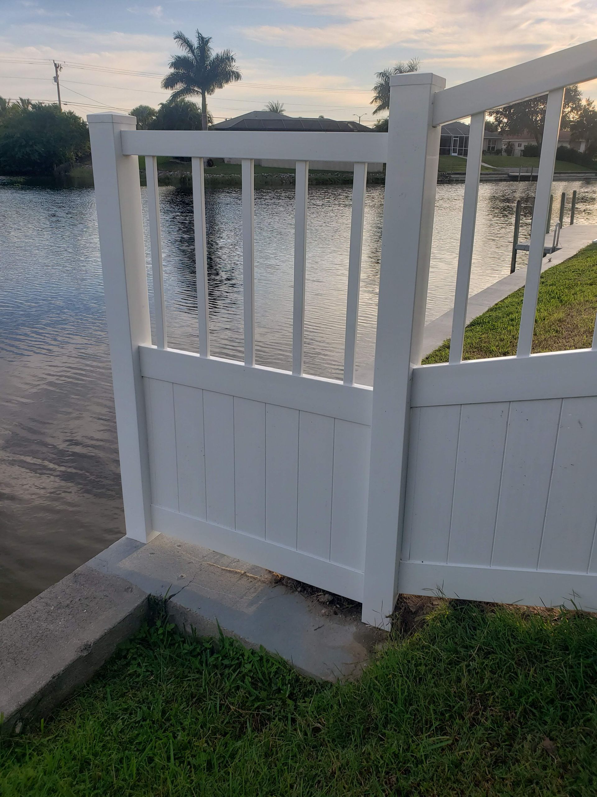 A white fence is sitting next to a body of water.