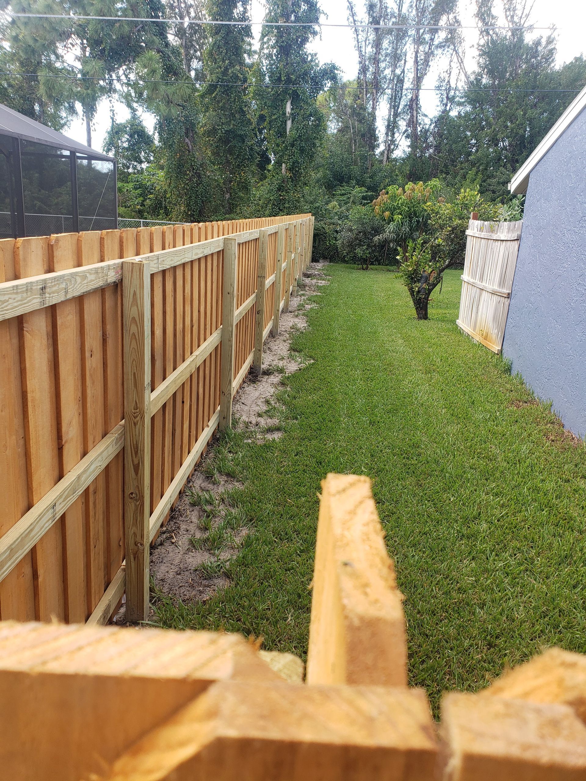 A wooden fence is sitting in the middle of a lush green yard.
