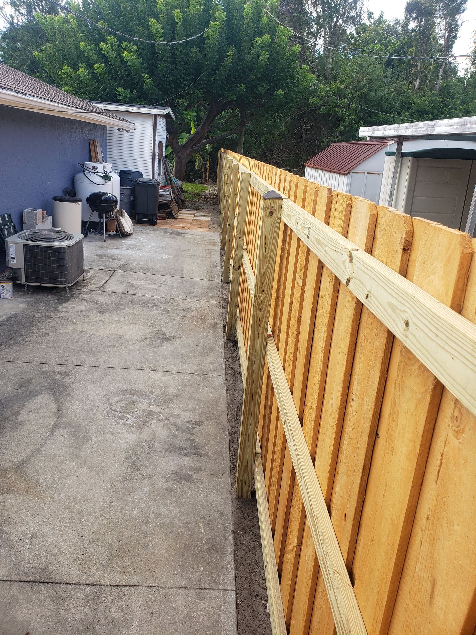 A wooden fence is being built in the backyard of a house.