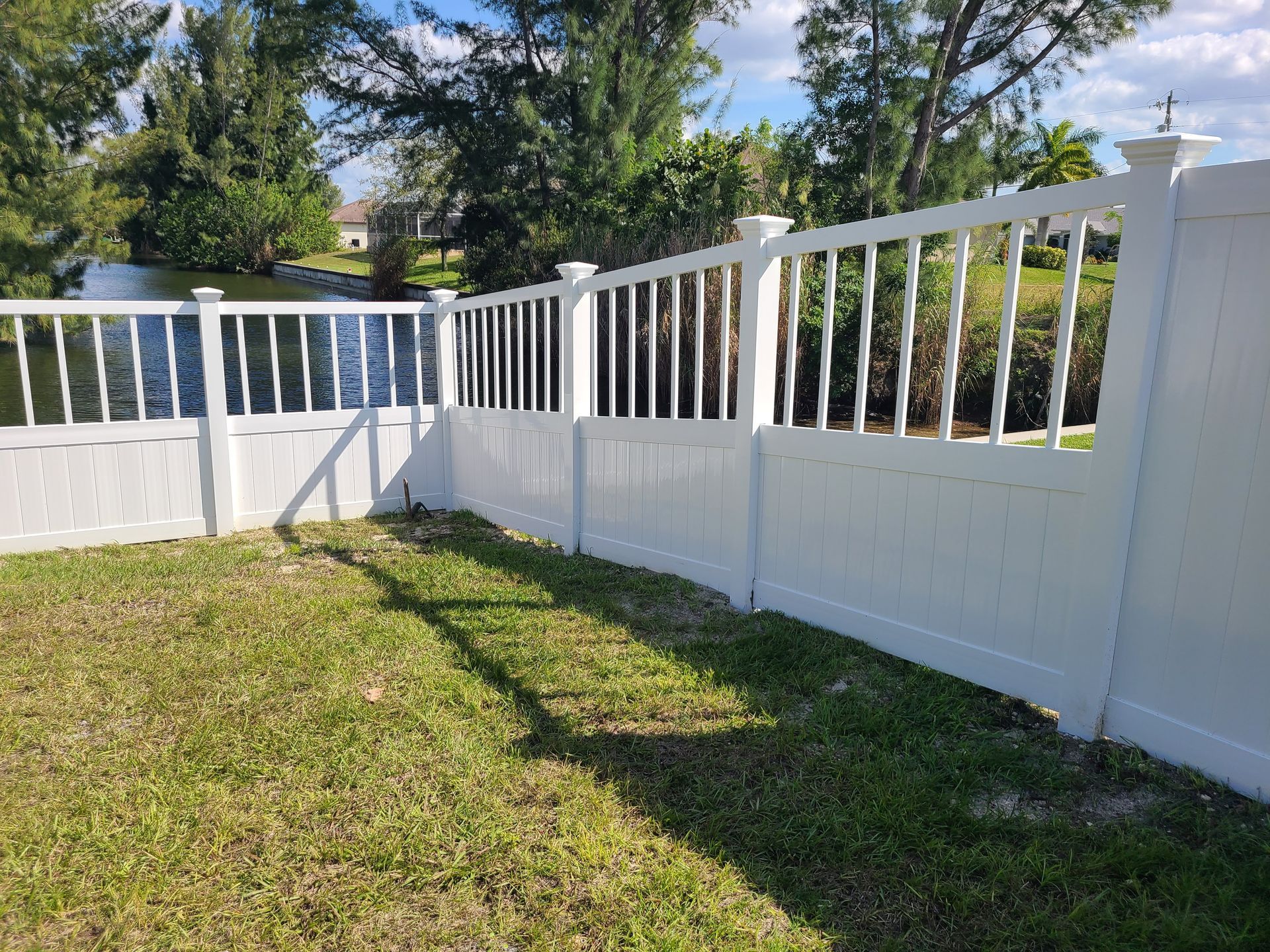 A white fence with a railing is in the middle of a lush green field.