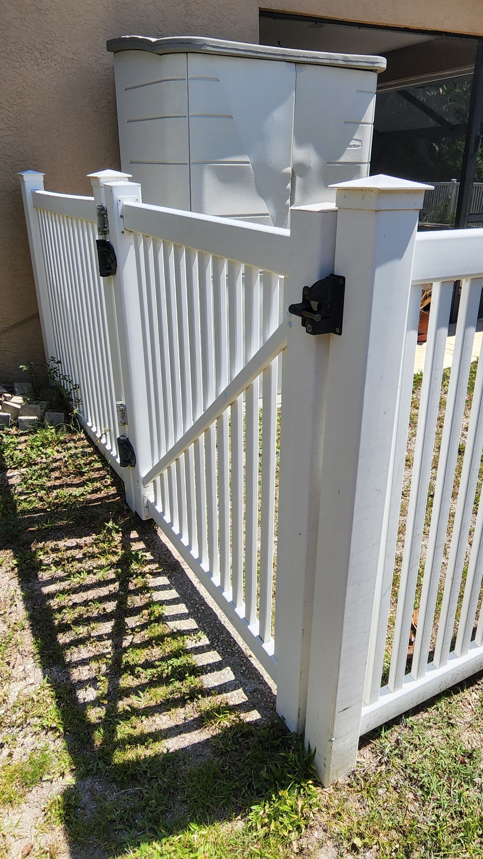 A white fence is sitting in the grass in front of a house.
