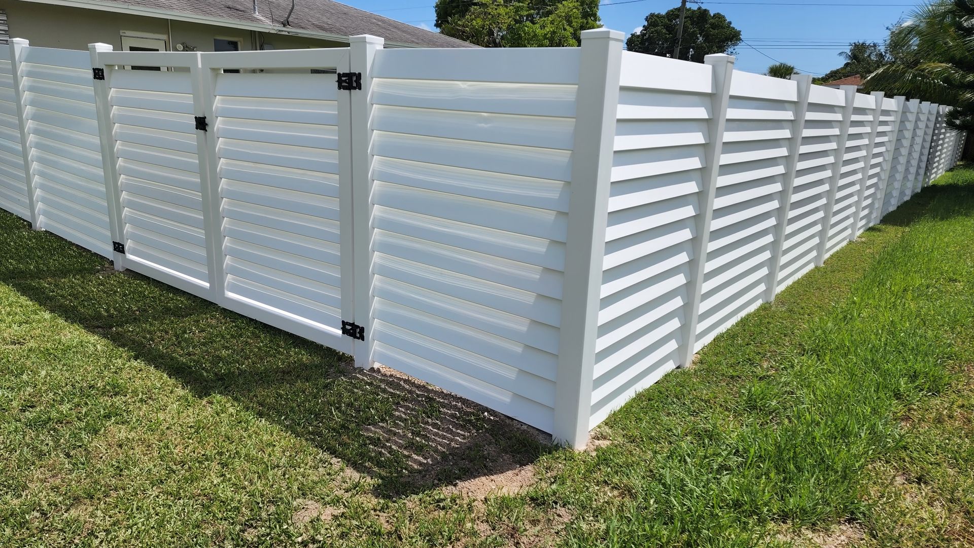 A white fence is sitting in the middle of a lush green field.