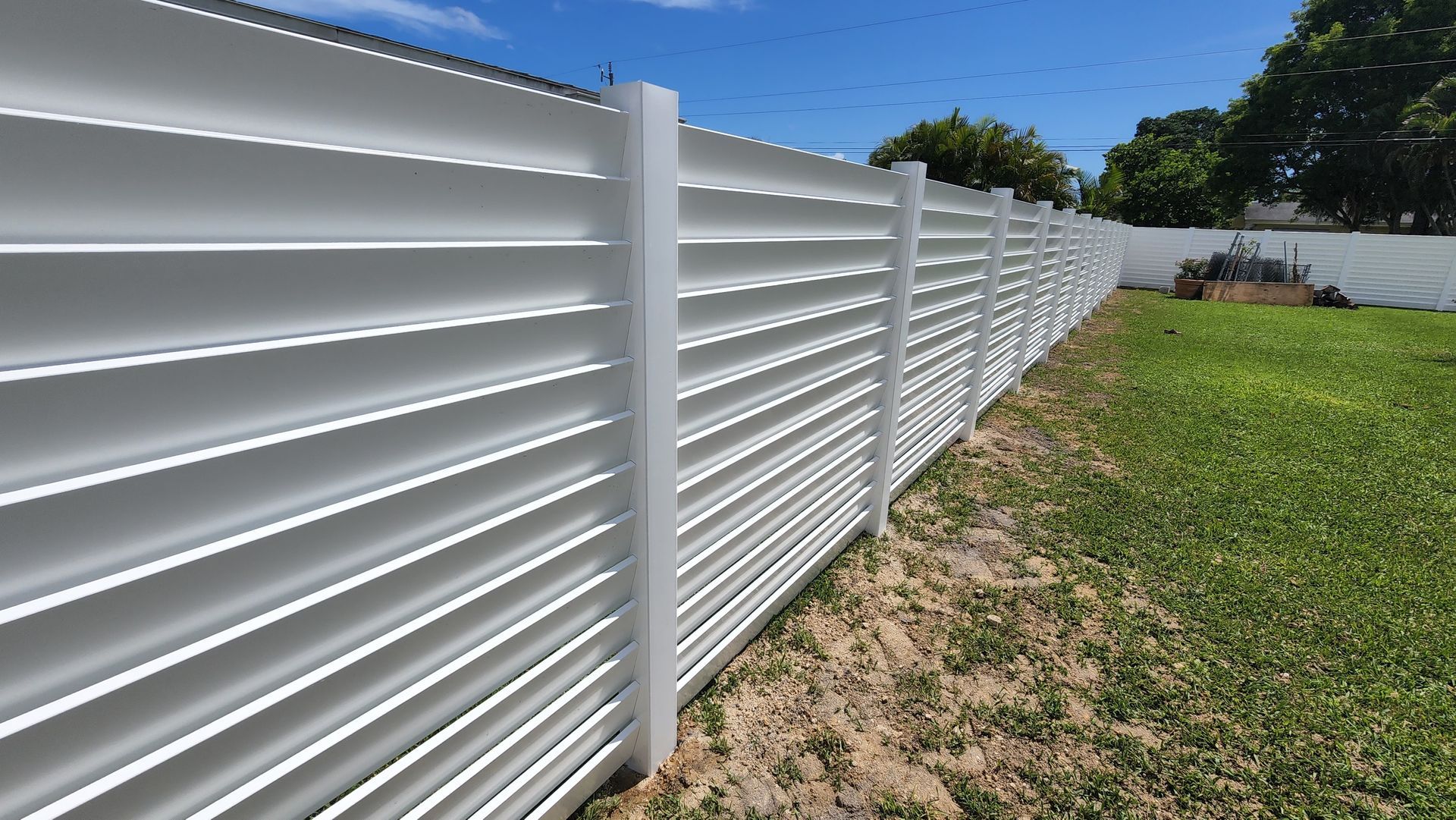 A white fence is sitting in the middle of a grassy field.