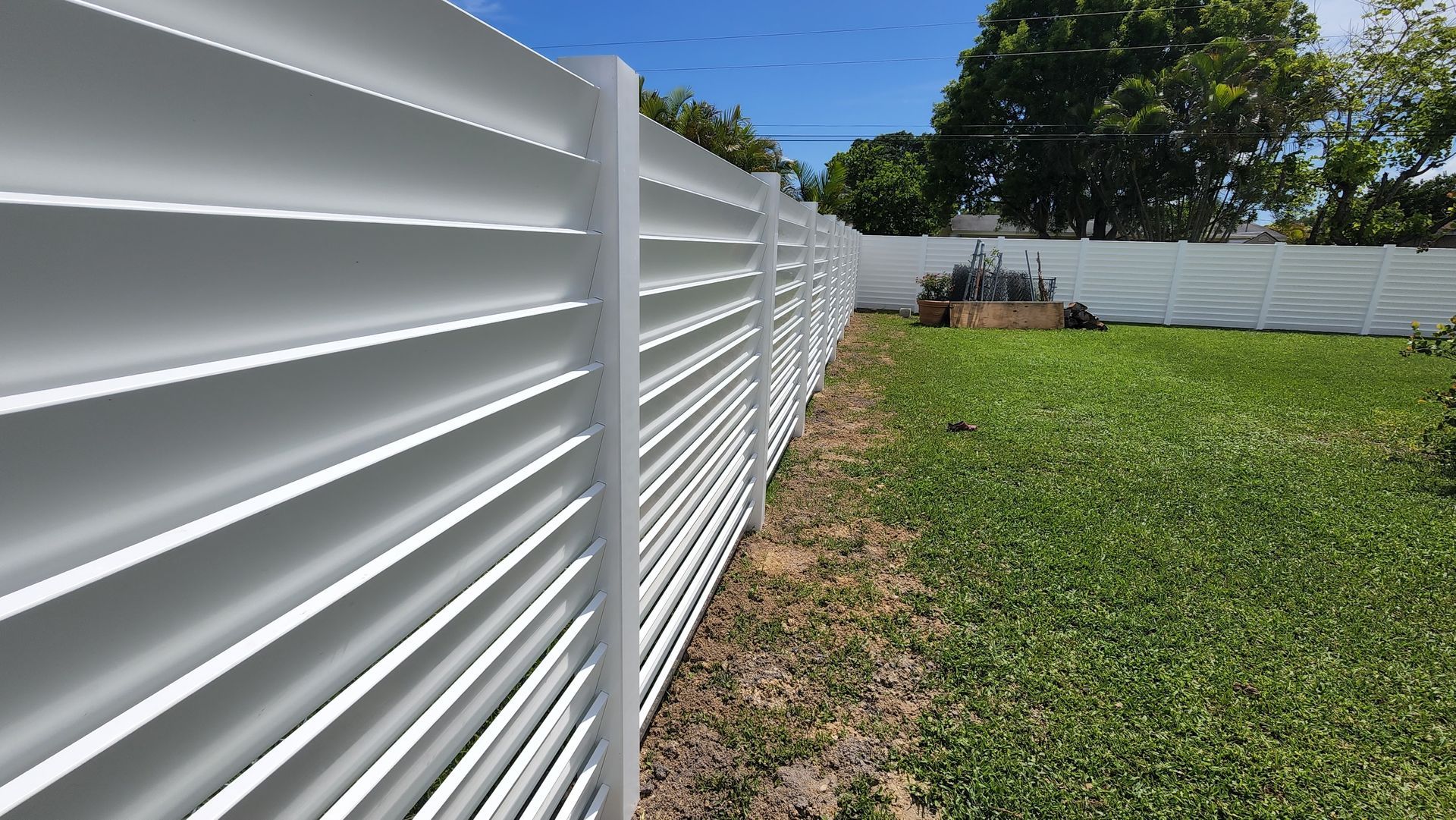 A white fence surrounds a lush green yard.