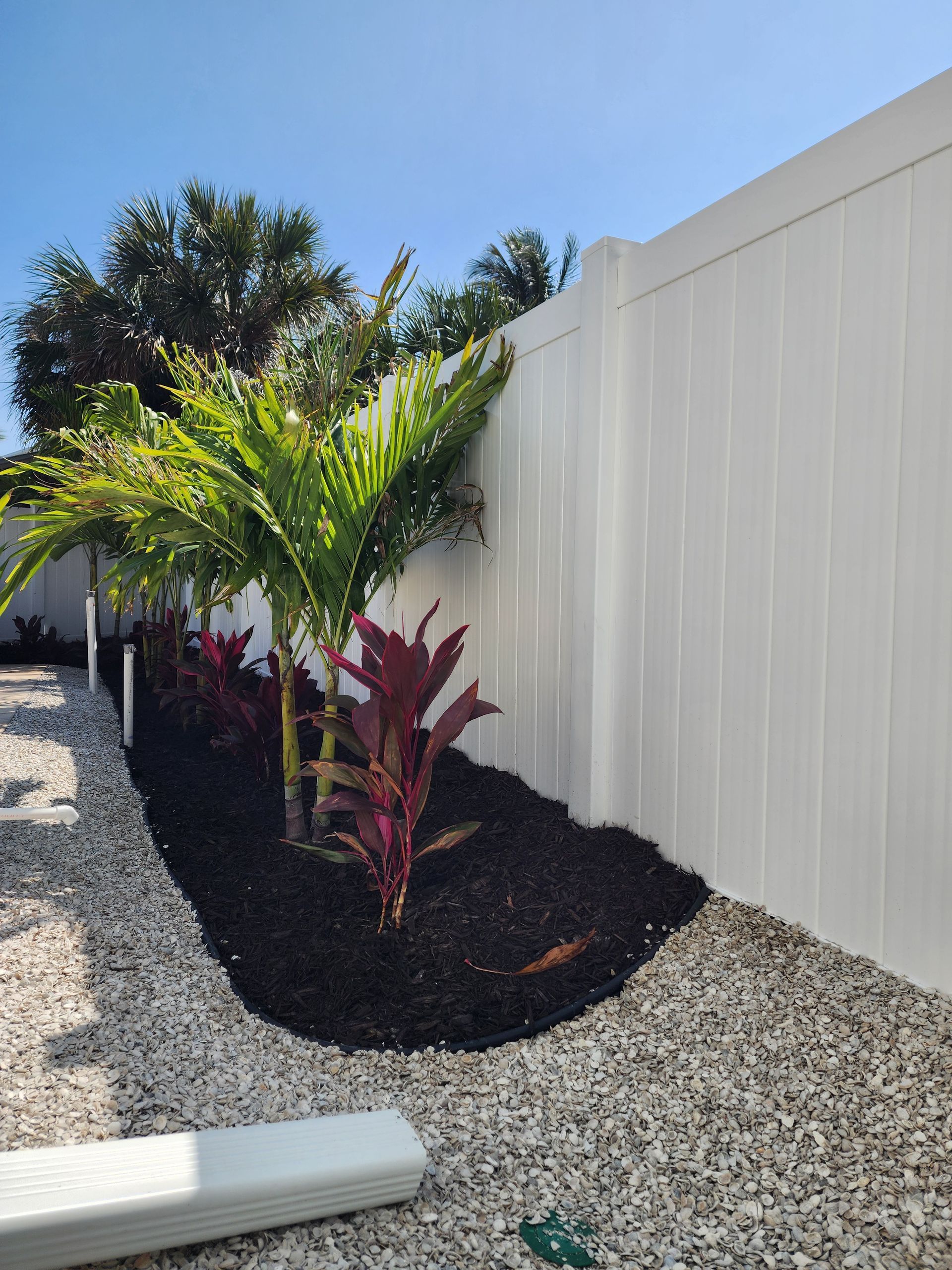 A white fence with a garden in front of it