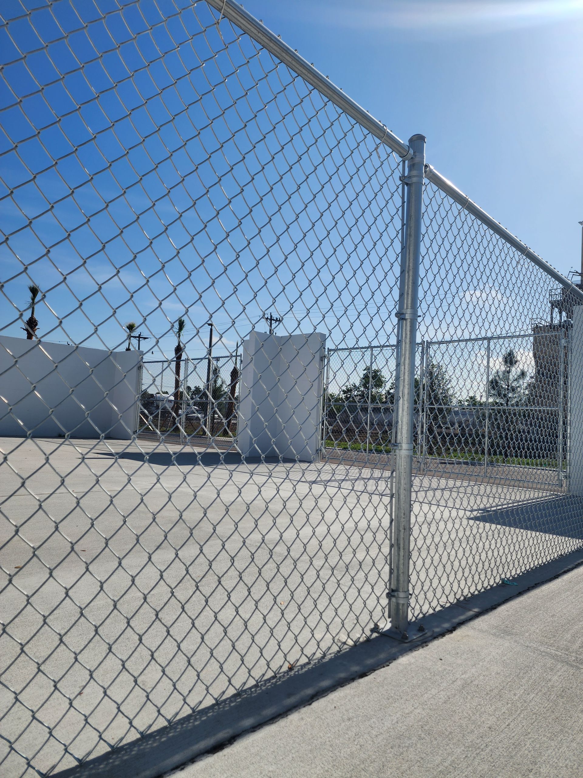 A chain link fence with a blue sky in the background.