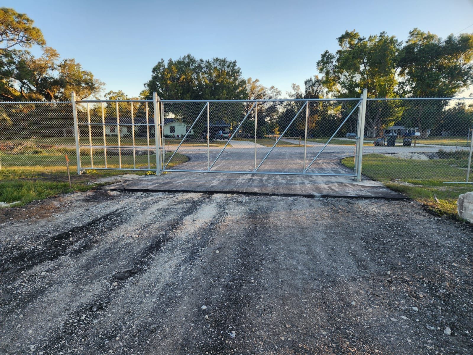 A chain link fence is surrounding a gravel road.