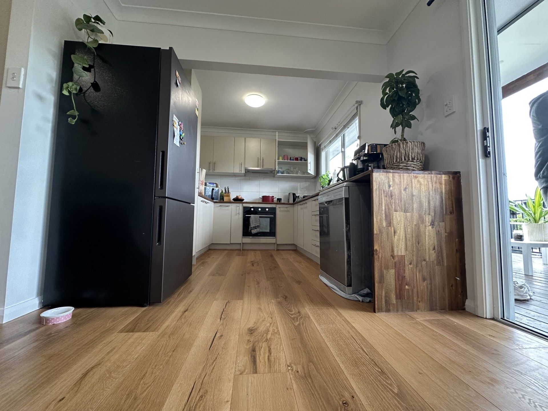 Bright kitchen and dining area with wood floors, black refrigerator, and white cabinets.