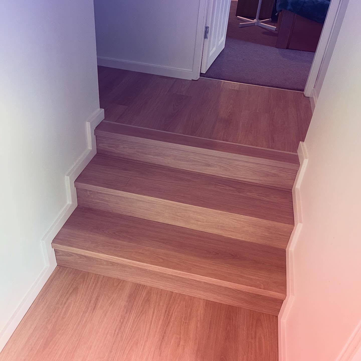 Wooden indoor staircase with three steps leading to a hallway carpet