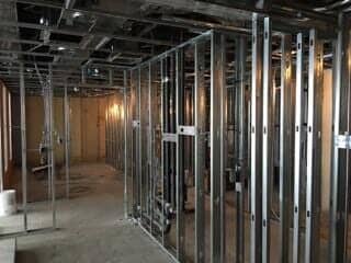 Unfinished room with exposed metal wall framing, concrete floor, and visible ceiling ducts.