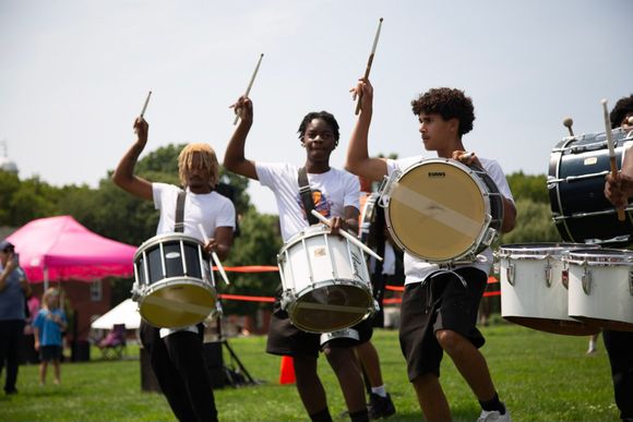 Cobra student drumline performing outdoors with drums raised in formation