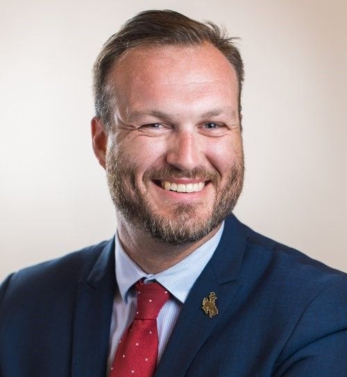 A man with a beard and a suit and tie is smiling for the camera.