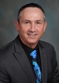 A man in a suit and tie is smiling for the camera.