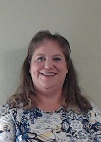 A woman in a floral shirt is smiling for the camera.