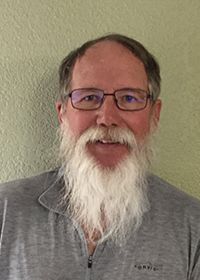A man with a beard and glasses is smiling for the camera.