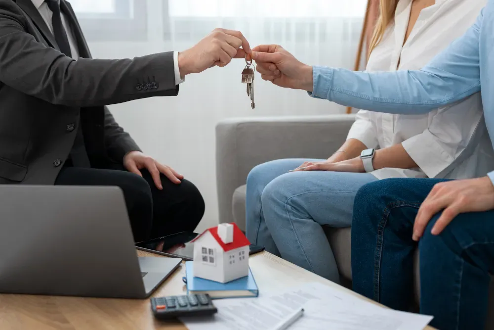 A man is handing a woman a set of keys while they are sitting on a couch.