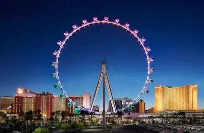 A large ferris wheel is lit up at night in a city.