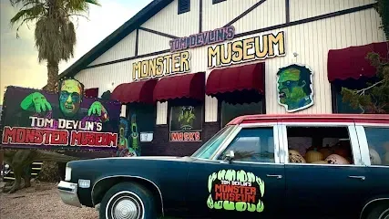 A black car is parked in front of a monster museum.