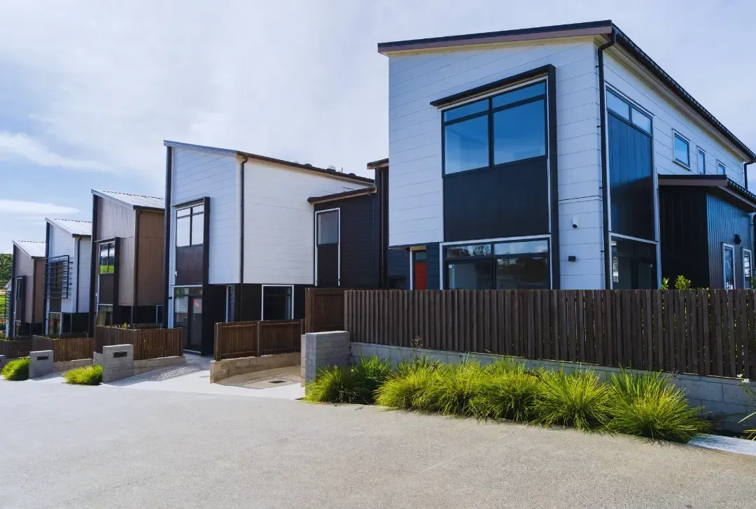 A row of modern houses with a wooden fence in front of them.