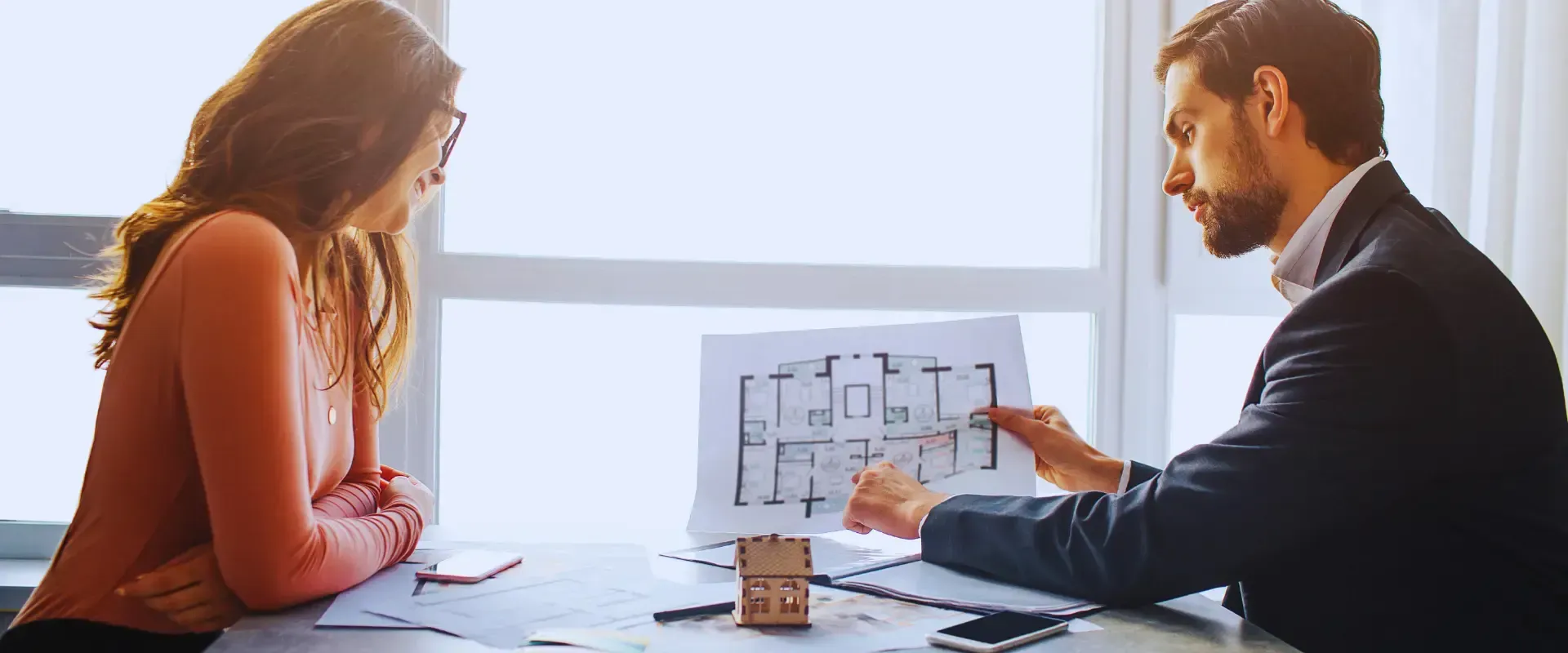 A man and a woman are sitting at a table looking at a house plan.