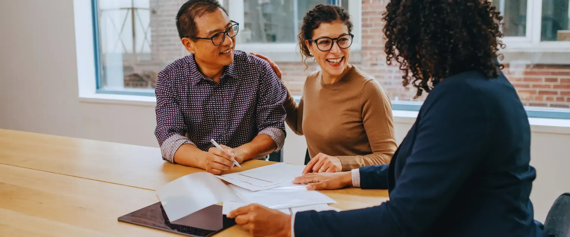 A man and a woman are sitting at a table talking to a woman.