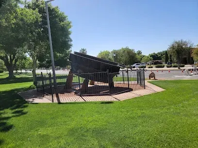 A large piano is sitting on top of a lush green field in a park.