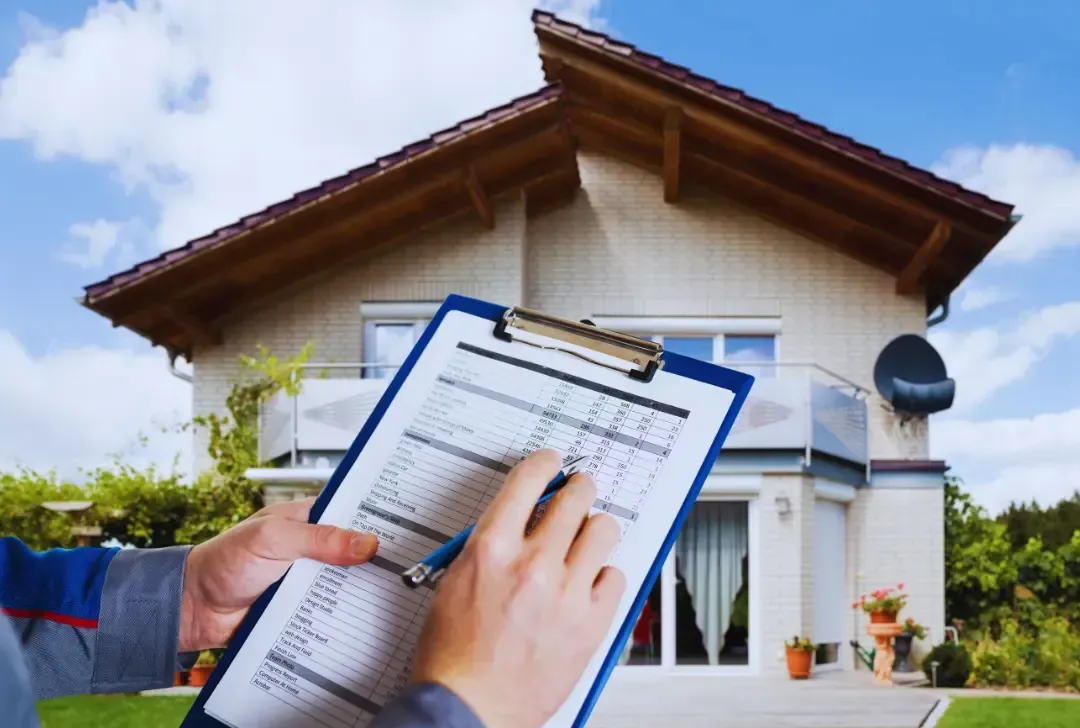 A person is holding a clipboard in front of a house