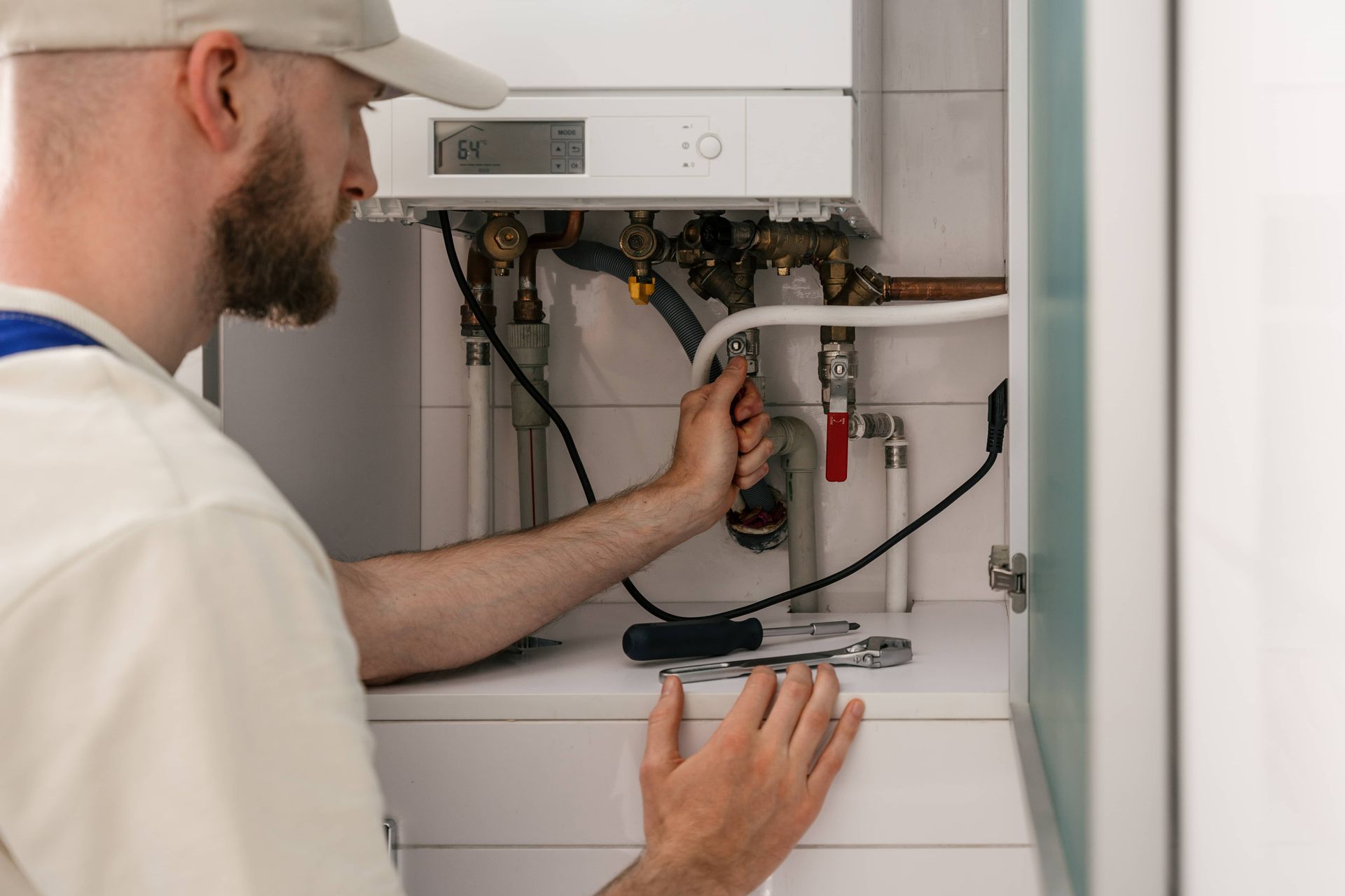 Technician inspecting open boiler with tools in a utility cabinet
