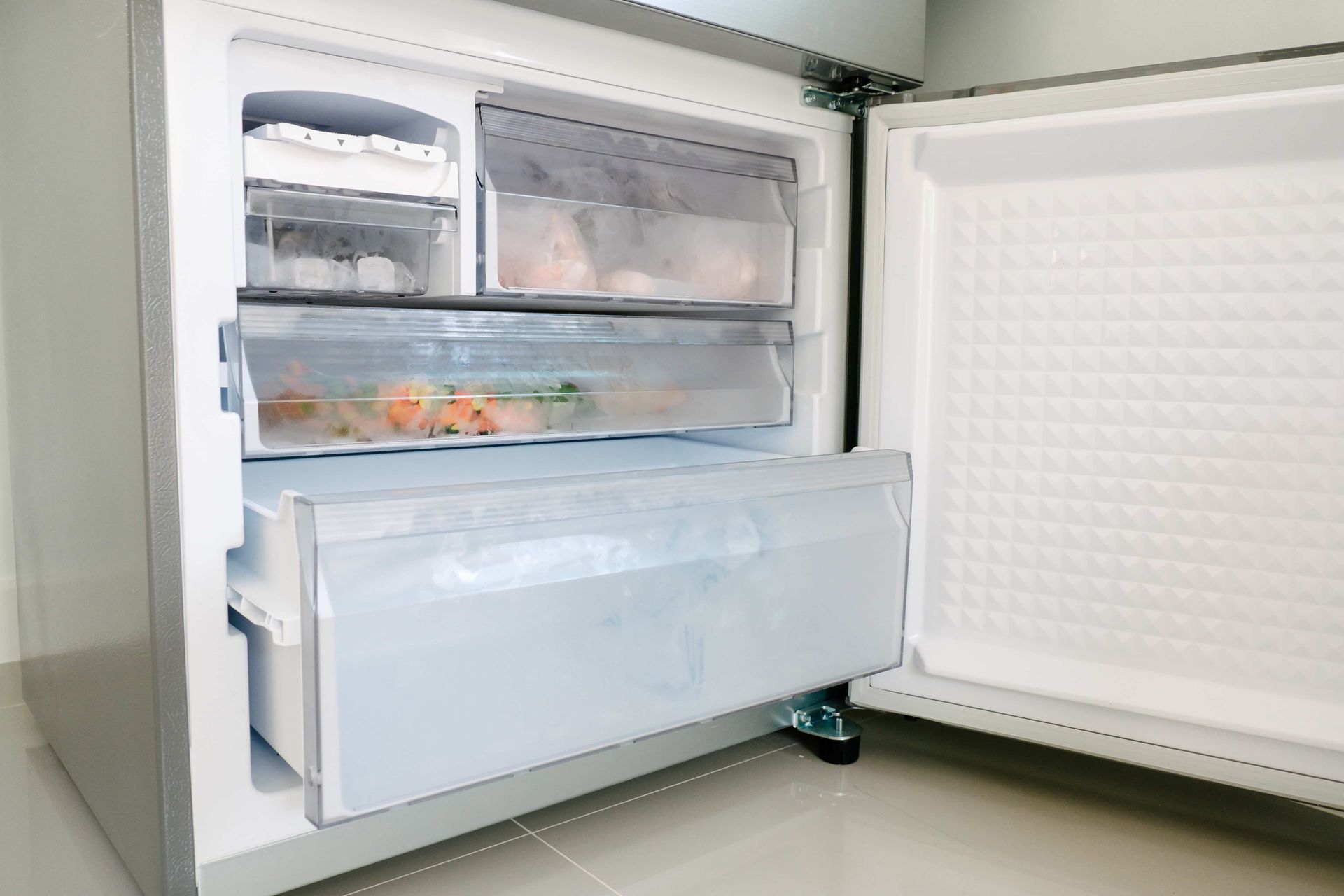 Open freezer drawers inside a white refrigerator, with food visible on the shelves.